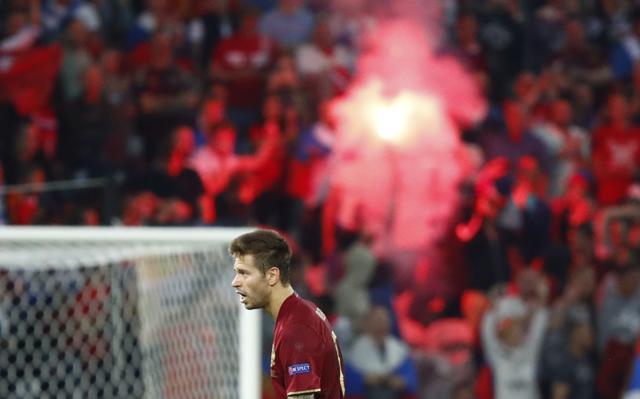 Russia's Fedor Smolov looks on as fans light a flare. (Reuters Photo) Russia's Fedor Smolov looks on as fans light a flare. (Reuters Photo)