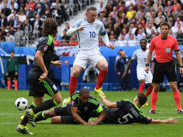 England's Wayne Rooney leaps over Wales players. (AP)