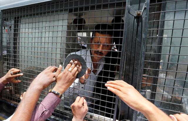 A convict in connection with a riot in Gujarat in 2002 gestures from inside a police vehicle at a court after the sentencing in Ahmedabad. (REUTERS)