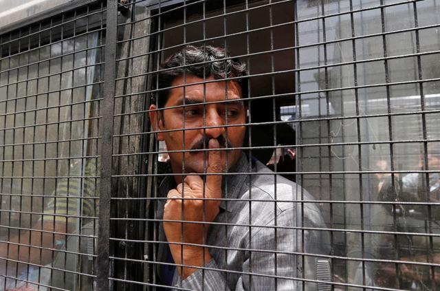 A convict in connection with a riot in Gujarat in 2002 gestures from inside a police vehicle at a court after the sentencing in Ahmedabad. (REUTERS)