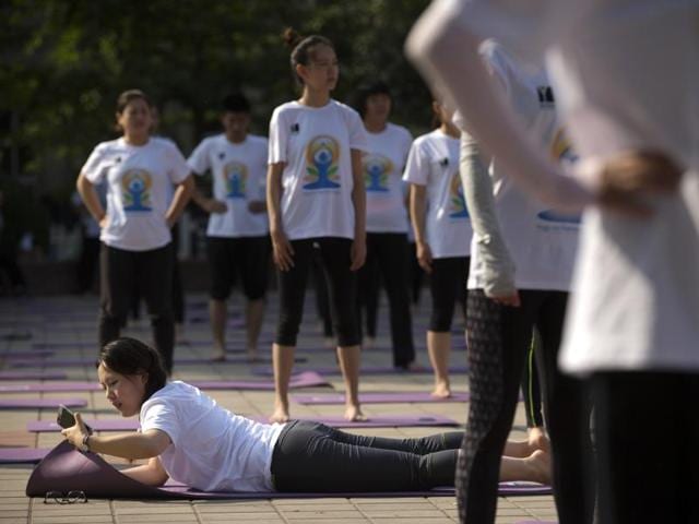 A participant checks her cellphone at the start of a group yoga session at a park in Beijing. (AP) 