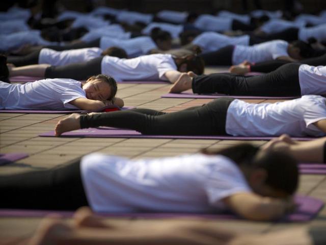 Participants stretch out during a group yoga session at a park in Beijing, Saturday, June 18, 2016.  (AP) 