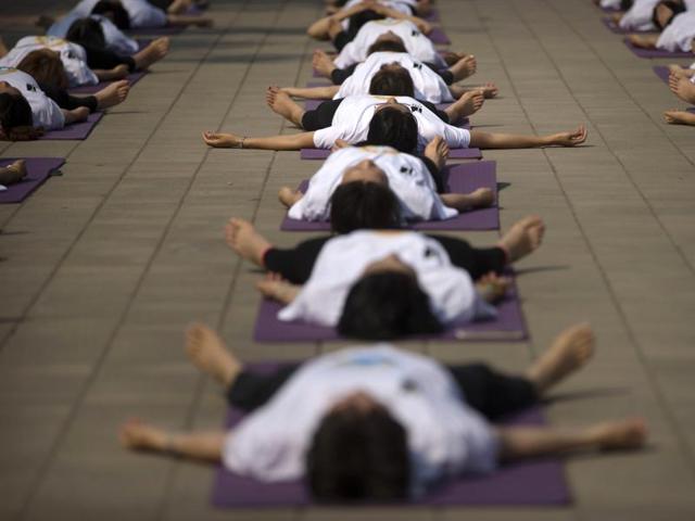 Participants relax at the end of a group yoga session at a park in Beijing, Saturday, June 18, 2016.  (AP) 