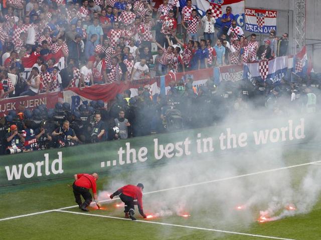 Stewards get the flares off the pitch. (REUTERS)