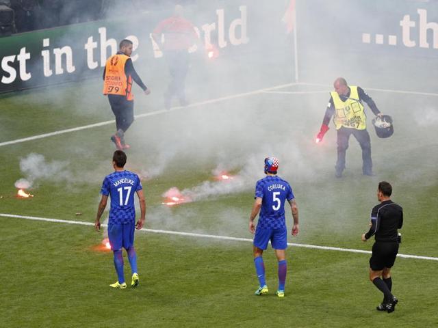 Players watch as the flares are cleared. (REUTERS)