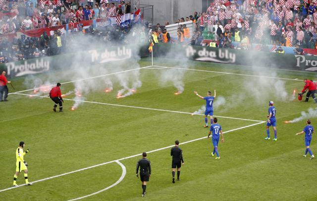 Stewards tend to flares thrown onto the pitch by fans as players look on. (REUTERS)