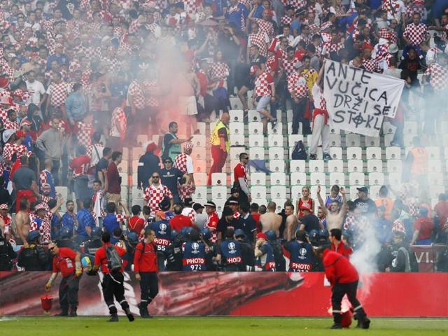 Stewards deal with flares thrown onto the pitch by fans. (REUTERS)