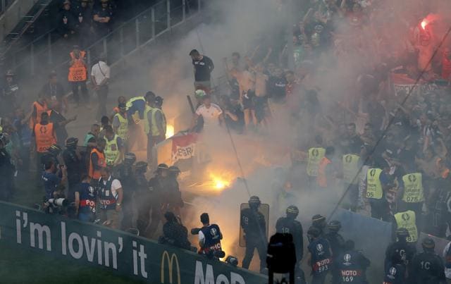 Stewards tend to a fire in the stands as fans light a flare as police stand ready. (REUTERS) Stewards tend to a fire in the stands as fans light a flare as police stand ready. (REUTERS)
