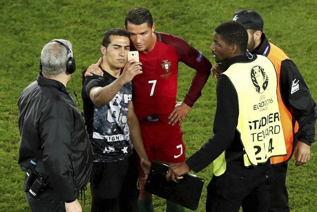 Portugal's Cristiano Ronaldo poses for a selfie with a man who invaded the pitch at the end of the Euro 2016 Group F football match between Portugal and Austria at the Parc des Princes stadium in Paris. (AP Photo) Portugal's Cristiano Ronaldo poses for a selfie with a man who invaded the pitch at the end of the Euro 2016 Group F football match between Portugal and Austria at the Parc des Princes stadium in Paris. (AP Photo)