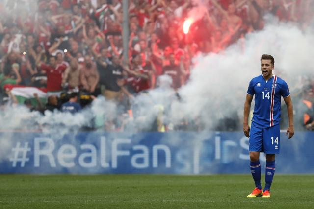 Iceland's Kari Arnason reacts as Hungary fans celebrate with flares after their first goal. (Reuters Photo) Iceland's Kari Arnason reacts as Hungary fans celebrate with flares after their first goal. (Reuters Photo)