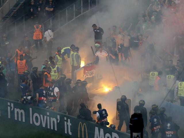 Stewards tend to a fire in the stands as fans light a flare, while police stay ready. (REUTERS)