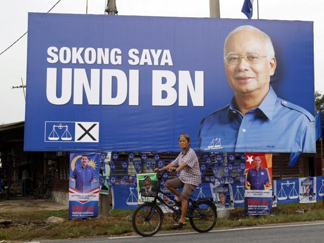 A Malaysian ethnic Chinese woman rides past a billboard of Malaysia's ruling National Front coalition with a portrait of Prime Minister Najib Razak. (AP File Photo) A Malaysian ethnic Chinese woman rides past a billboard of Malaysia's ruling National Front coalition with a portrait of Prime Minister Najib Razak. (AP File Photo)