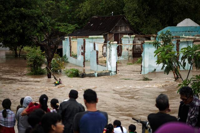 People stand in front of a flooded area in Kampung Sewuresidential area in Solo, Central Java province, Indonesia, June 19, 2016. (REUTERS)