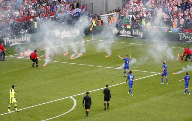 Stewards tend to flares thrown onto the pitch by fans as players look on. (Reuters)