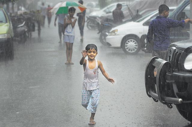 A kid soaks in rain in New Delhi on June 20, 2016. Heavy downpour caused water logging and traffic jams in the city. (Burhaan Kinu / Hindustan Times)