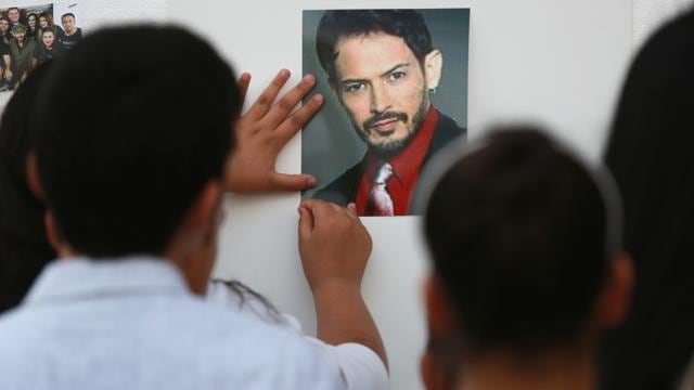 A child posts a photograph of Alejandro "Jano" Fuentes outside Tras Bambalinas music school during a memorial in Chicago. (AP)