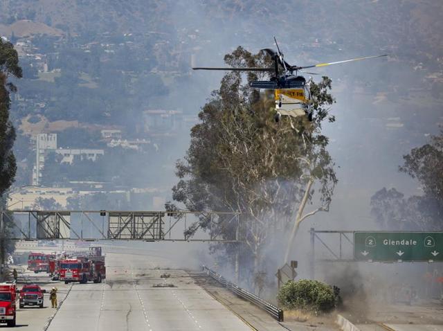 Firefighters use a helicopter to douse a fire near California State Route 2. (AP) Firefighters use a helicopter to douse a fire near California State Route 2. (AP)