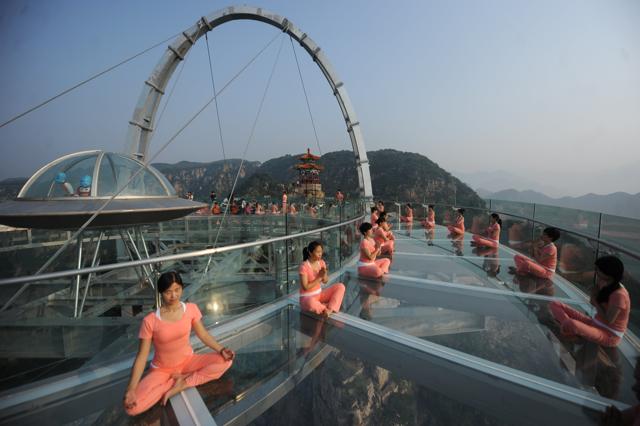 People practise yoga at a glass sightseeing platform on the outskirts of Beijing, China. (REUTERS) People practise yoga at a glass sightseeing platform on the outskirts of Beijing, China. (REUTERS)