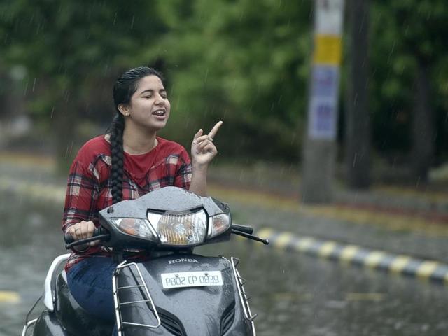A girl seems to be talking to the rain as she rides through the showers in Amritsar on Wednesday. (Gurpreet Singh/HT)