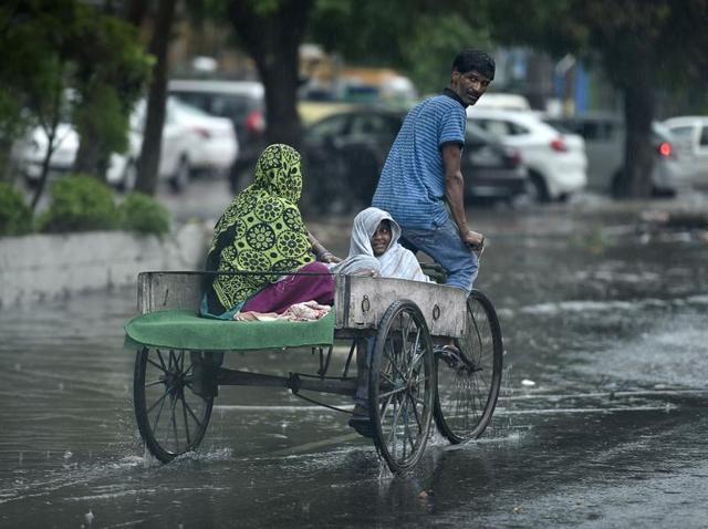 Commuters on a waterlogged road on a rainy day in Amritsar. (Gurpreet Singh/HT)