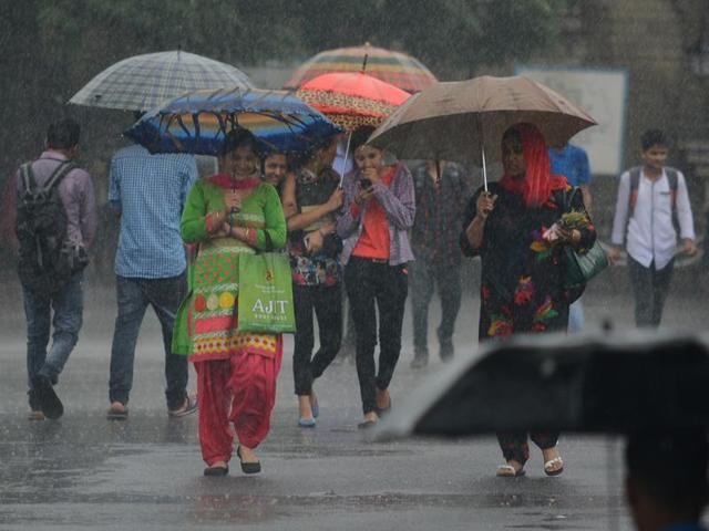 Some hide under umbrellas while others feel the rain at The Ridge in Shimla on Wednesday. (Deepak Sansta/HT)