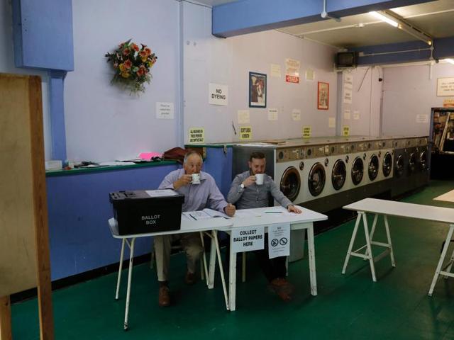 A presiding officer (L) and poll clerk (C) drink a cup of tea while waiting for early morning voters at a polling station set up in a launderette in Headington outside Oxford. (AFP) 