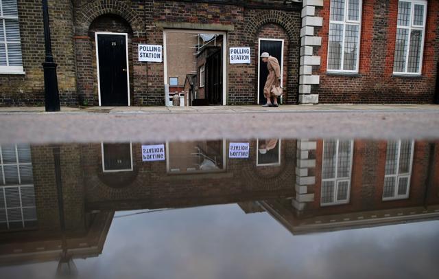 An elderly woman is reflected in a puddle of rain water as she arrives at a polling station at the Royal Hospital in Chelsea in London on June 23, 2016. (AFP) An elderly woman is reflected in a puddle of rain water as she arrives at a polling station at the Royal Hospital in Chelsea in London on June 23, 2016. (AFP)