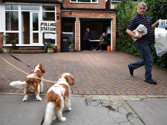 The owner of a house whose garage is being used as a polling station takes out his rubbish in Croydon, south of London. Millions of Britons began voting today in a bitterly-fought, knife-edge referendum that could tear up the island nation's EU membership.(AFP)