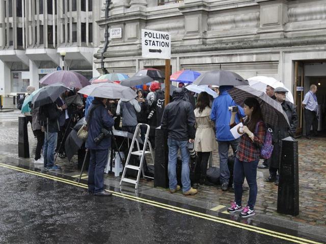 Media shelter under umbrellas as they wait for the British Prime Minister David Cameron and his wife Samantha to cast their votes in the EU referendum at a polling station in London. (AP Photo) 