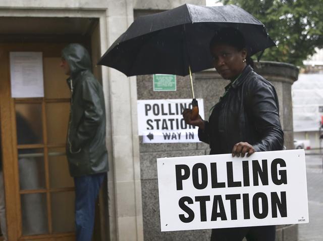 A woman carries an umbrella and a polling station sign at a polling station for the Referendum on the European Union in north London in Britain on June 23, 2016. (REUTERS) A woman carries an umbrella and a polling station sign at a polling station for the Referendum on the European Union in north London in Britain on June 23, 2016. (REUTERS)