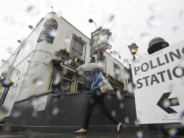 A woman carries an umbrella past a pub being used as a polling station for the Referendum on the European Union in west London, Britain, June 23, 2016.(Reuters Photo)