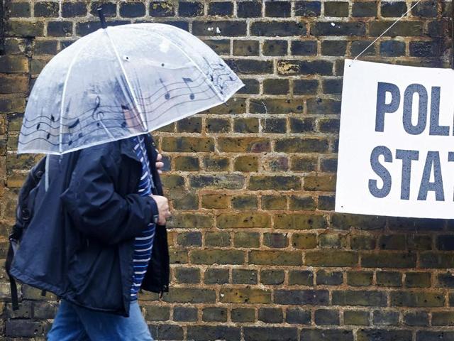 A man shelters from the rain as he arrives at a polling station in London, as Britain holds a referendum on wether to stay in, or leave the European Union (EU).  (AFP) 