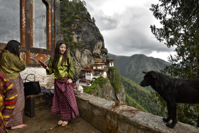 A young woman checks her mobile phone after paying obeisance at the Taksang Monastery (or Tiger’s Nest), where Guru Padmasambhava meditated. (Gurinder Osan/HT PHOTO) A young woman checks her mobile phone after paying obeisance at the Taksang Monastery (or Tiger’s Nest), where Guru Padmasambhava meditated. (Gurinder Osan/HT PHOTO)