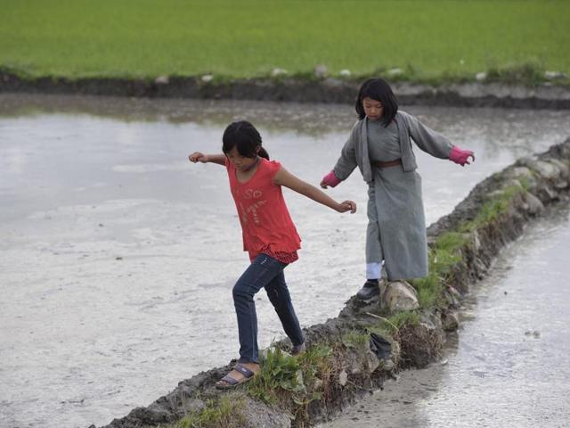 Girls walk through a paddy field in Paro, Bhutan, on Tuesday, June 14, 2016. (Gurinder Osan/HT PHOTO)