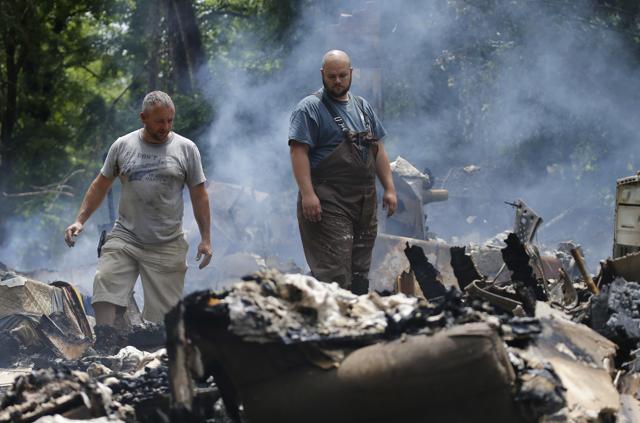 Mark Lester, left, and a local firefighter look through the remnants of the Ron Scott’s home. A deluge of 9 inches of rain on parts of West Virginia destroyed or damaged more than 100 homes and knocked out power to tens of thousands of homes and businesses.  (AP)