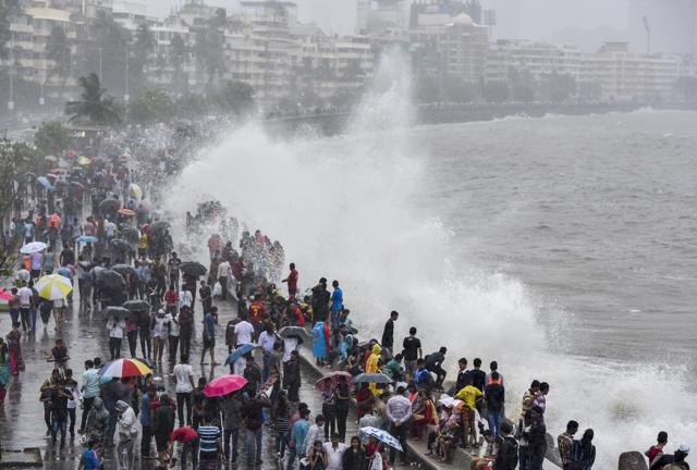 Residents and tourists enjoy a high tide at Marine Drive in Mumbai. People often flock to the tourist hot spot to enjoy the rain. (Kunal Patil)