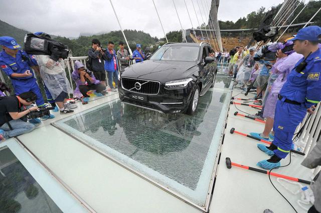 A sedan car filled with passengers drives across a glass-bottomed suspension bridge after the top layer of glass was deliberately cracked during tests. (AP) A sedan car filled with passengers drives across a glass-bottomed suspension bridge after the top layer of glass was deliberately cracked during tests. (AP)