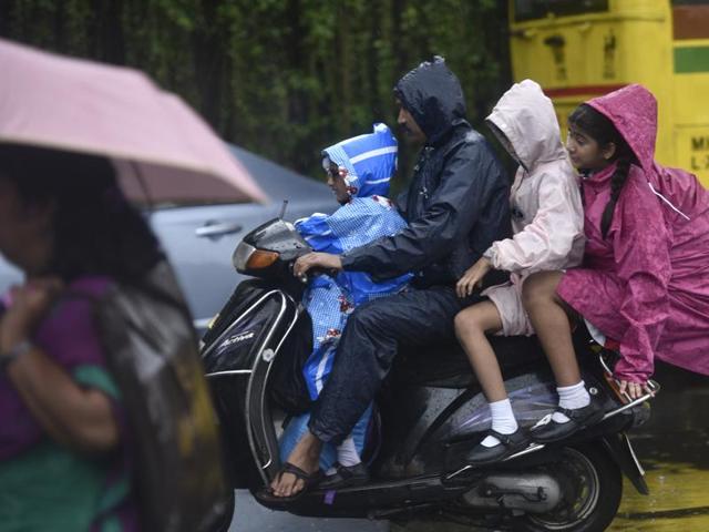 Children slip inside raincoats while returning from school during heavy rain in Mumbai on Friday. (Arijit Sen)