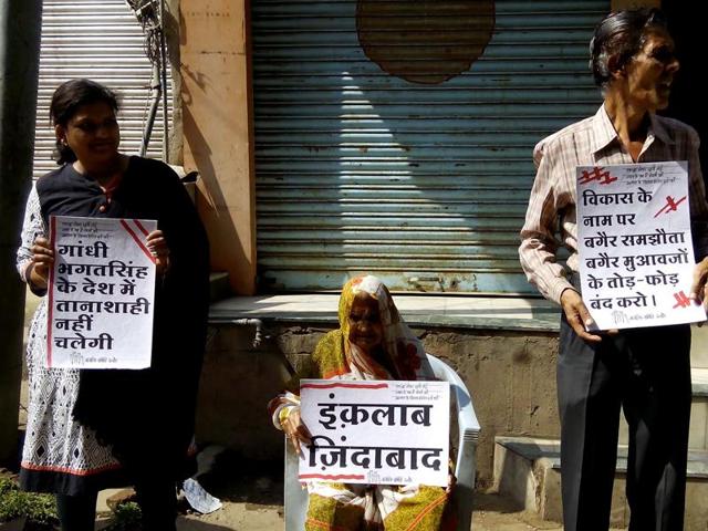 Residents of Juni hold placards protesting against Indore demolition drive in the name of ‘Smart City’ development.(HT photo)