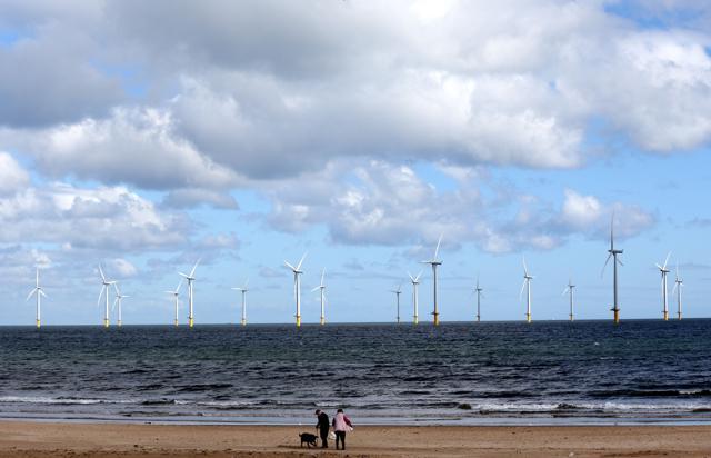 People walk on the beach as the wind turbines stretch out into the sea in Redcar. (AFP) People walk on the beach as the wind turbines stretch out into the sea in Redcar. (AFP)