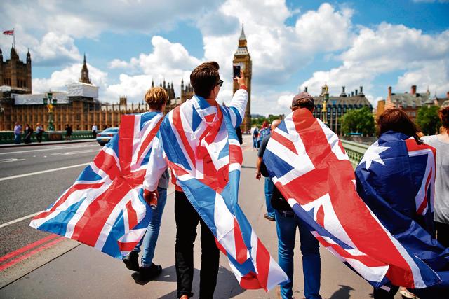 People walk over Westminster Bridge wrapped in Union flags, towards the Queen Elizabeth Tower (Big Ben) and The Houses of Parliament in central London on June 26, 2016.(AFP)