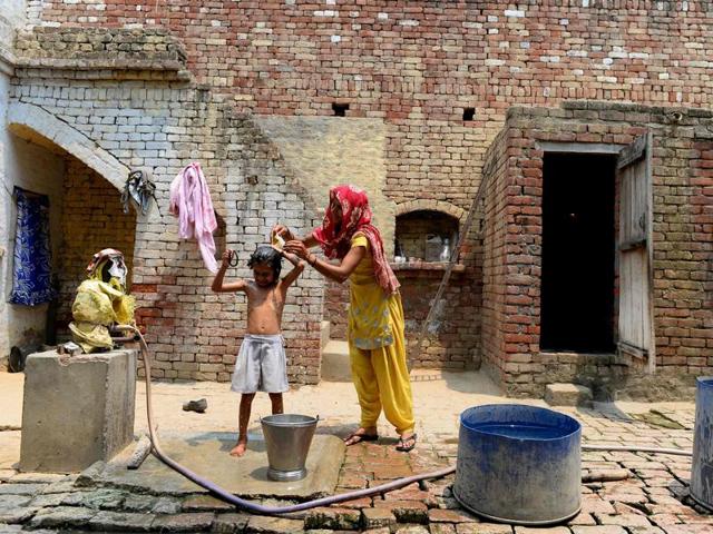 In this photograph taken on May 8, 2016, a woman bathes her daughter with contaminated water at her home in the village of Gangnauli in Uttar Pradesh.(AFP Photo)