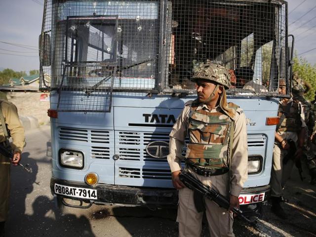 Security personnel stand guard near a damaged bus that was carrying CRPF personnel after a highway ambush by militants in Pampore, on the outskirts of Srinagar, on June 25, 2016. Eight jawans were killed in the ambush.(Waseem Andrabi / HT Photo)
