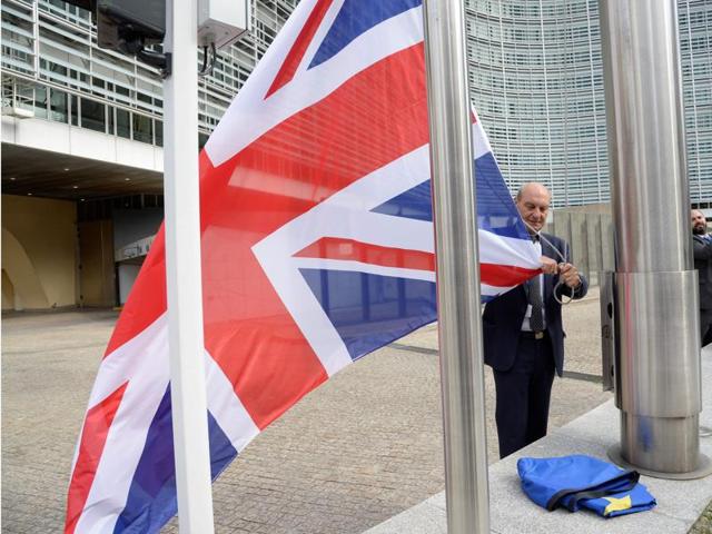 A member of the Commission removes a British flag during a European Summit at the EU headquarters in Brussels.(AFP Photo)