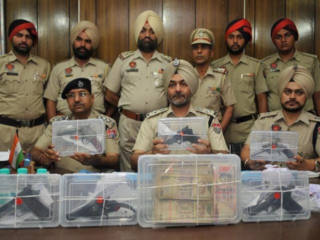 Assistant inspector general HPS Khakh (centre) and other officers showing the seized pistols and cash at a press conference in Jalandhar on Wednesday.(Pardeep Pandit/HT Photo)