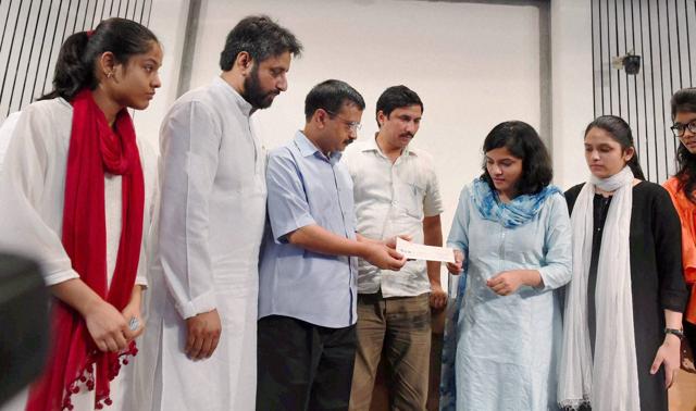 Arvind Kejriwal present a cheque to daughters of slain NDMC official MM Khan. (PTI)