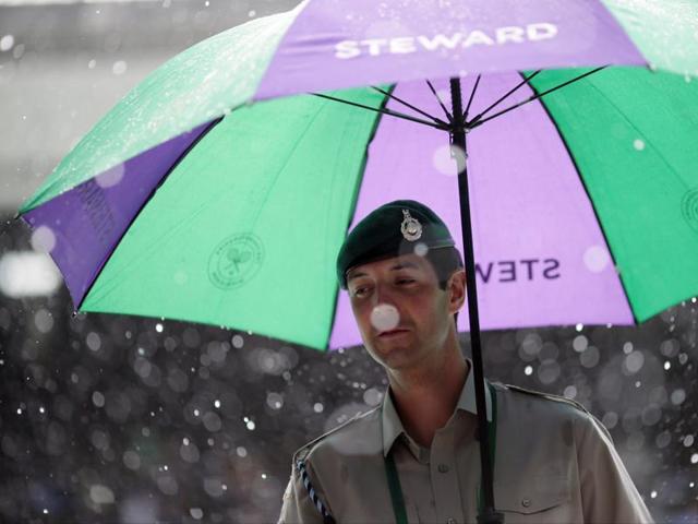 A steward takes shelter under an umbrella. (AP) A steward takes shelter under an umbrella. (AP)