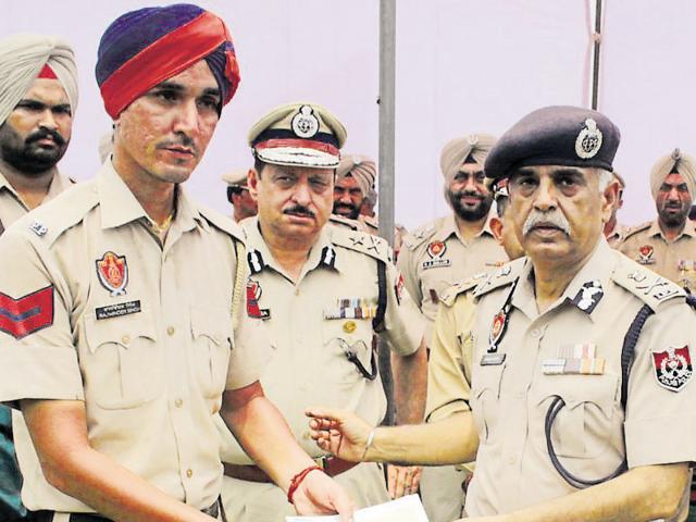 Director general of police Suresh Arora honouring a constable in Jalandhar on Friday.(HT photo)