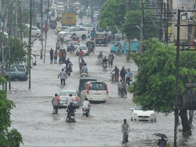 Commuters wading through a water-logged road in Jalandhar on Saturday. (Pardeep Pandit/HT Photo)