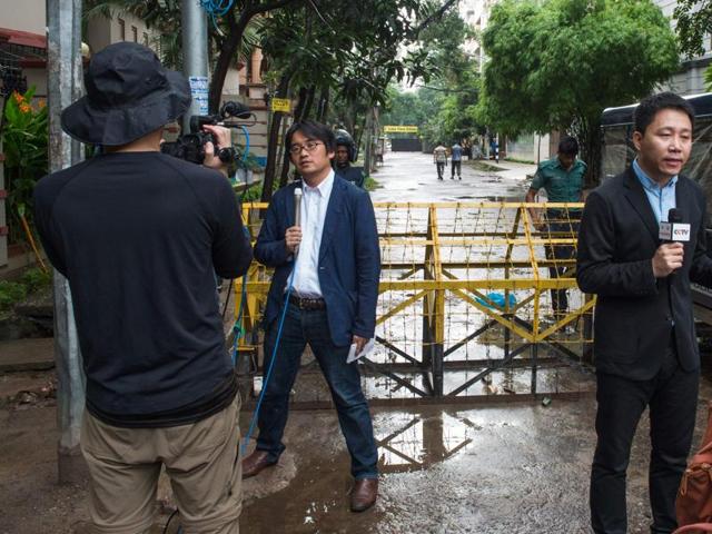 A Japanese TV crews report from a barricade down the street from the scene of the attack on Sunday. Nine Italians, seven Japanese nationals, an Indian and a US national were among the dead. Thirteen hostages were rescued, including one Japanese national and two Sri Lankans. (AFP)